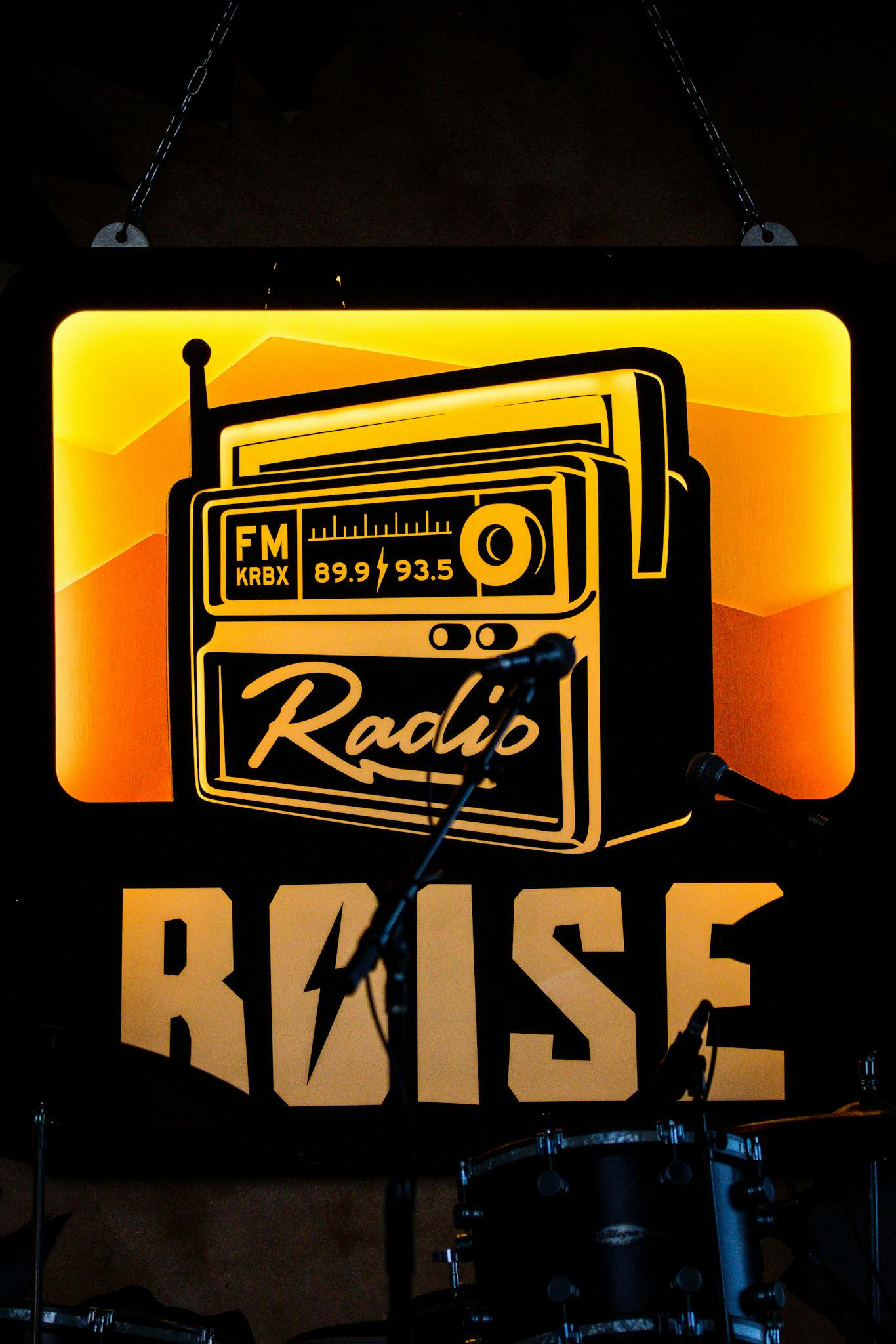 Retro radio sign with microphones and drums at a Boise music venue, highlighting local vibes.